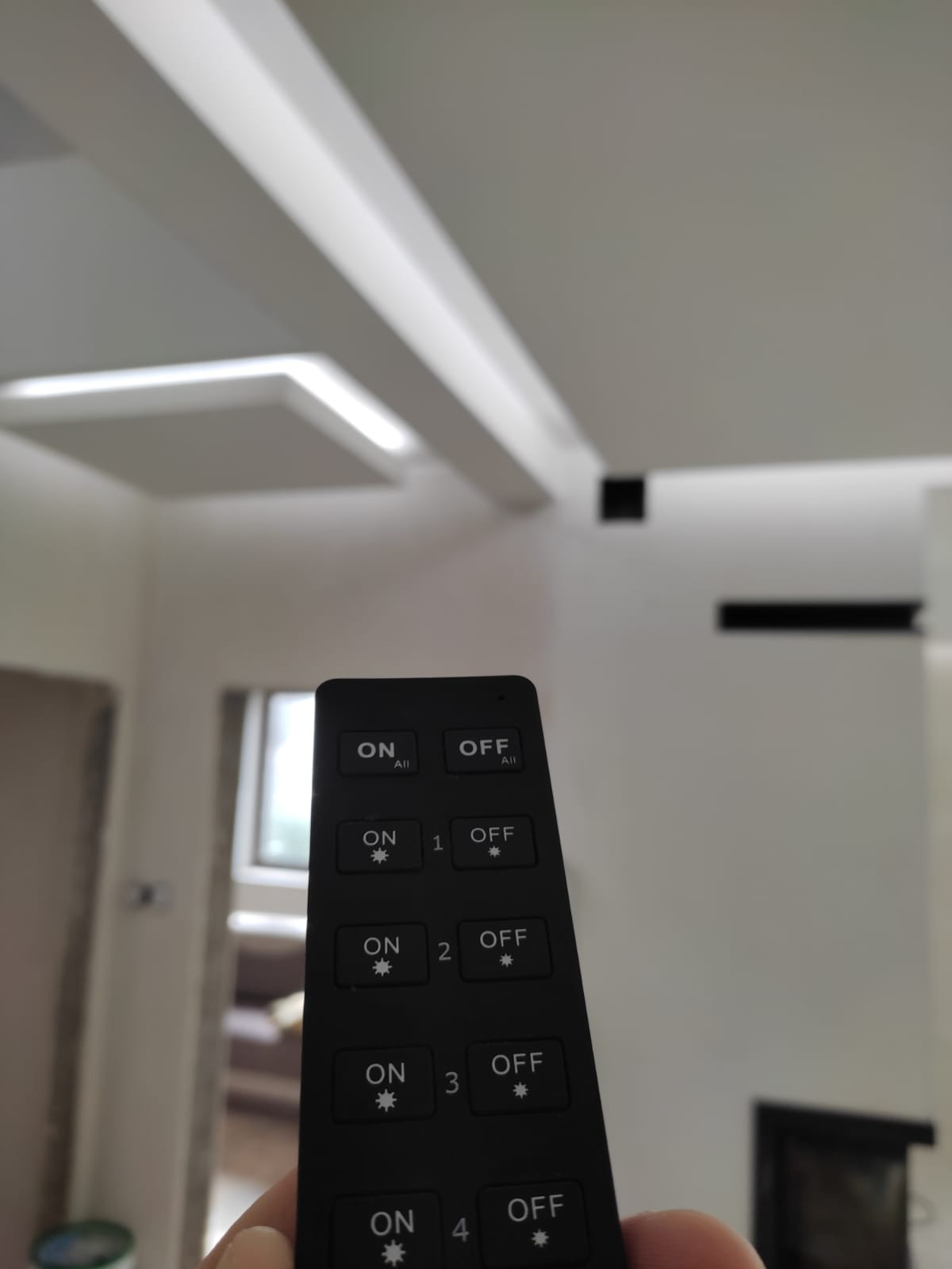 Nowoczesny sufit z oświetleniem LED sterowany pilotem, widoczne włączniki i wyłączniki poszczególnych sekcji.