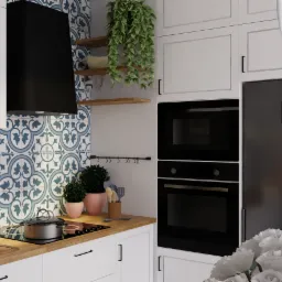Nowoczesna kuchnia z białymi szafkami, czarnym okapem i piekarnikiem, oraz dekoracyjnymi płytkami w niebieskie wzory. Na blacie stoi garnek na płycie indukcyjnej, obok doniczki z zielonymi...