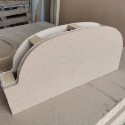 Półokrągły element z płyty MDF z drewnianymi wzmocnieniami, prawdopodobnie fragment większej konstrukcji, leżący na stosie płyt w warsztacie.