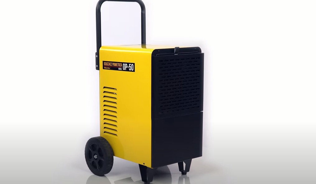 Żółto-czarny mobilny osuszacz powietrza Warmtec OP-50 na kółkach, używany przez firmy z Olsztyna do osuszania budynków po zalaniach.