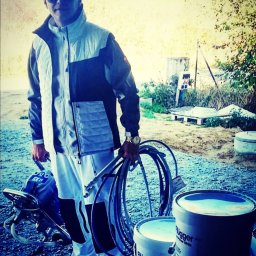 Tomdeco - Mężczyzna w okularach przeciwsłonecznych trzymający wąż do agregatu malarskiego, obok stoją wiadra z farbą Flugger White