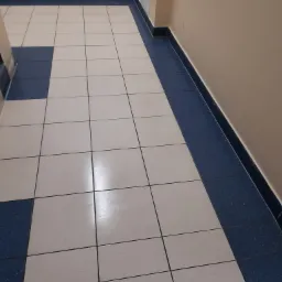 Biało-szara podłoga z płytek w korytarzu z niebieskimi cokołami i listwami przypodłogowymi, widok z góry.