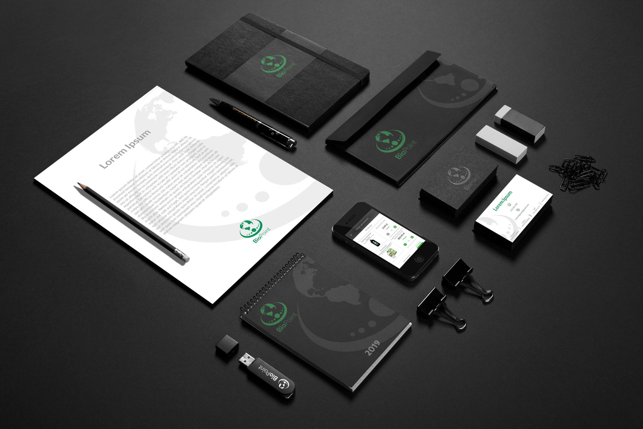 Makieta identyfikacji wizualnej firmy BioPoint na czarnym tle: papier firmowy z tekstem Lorem Ipsum, notatnik, pendrive, wizytówki, koperta, smartfon z widokiem sklepu internetowego, ołówek...