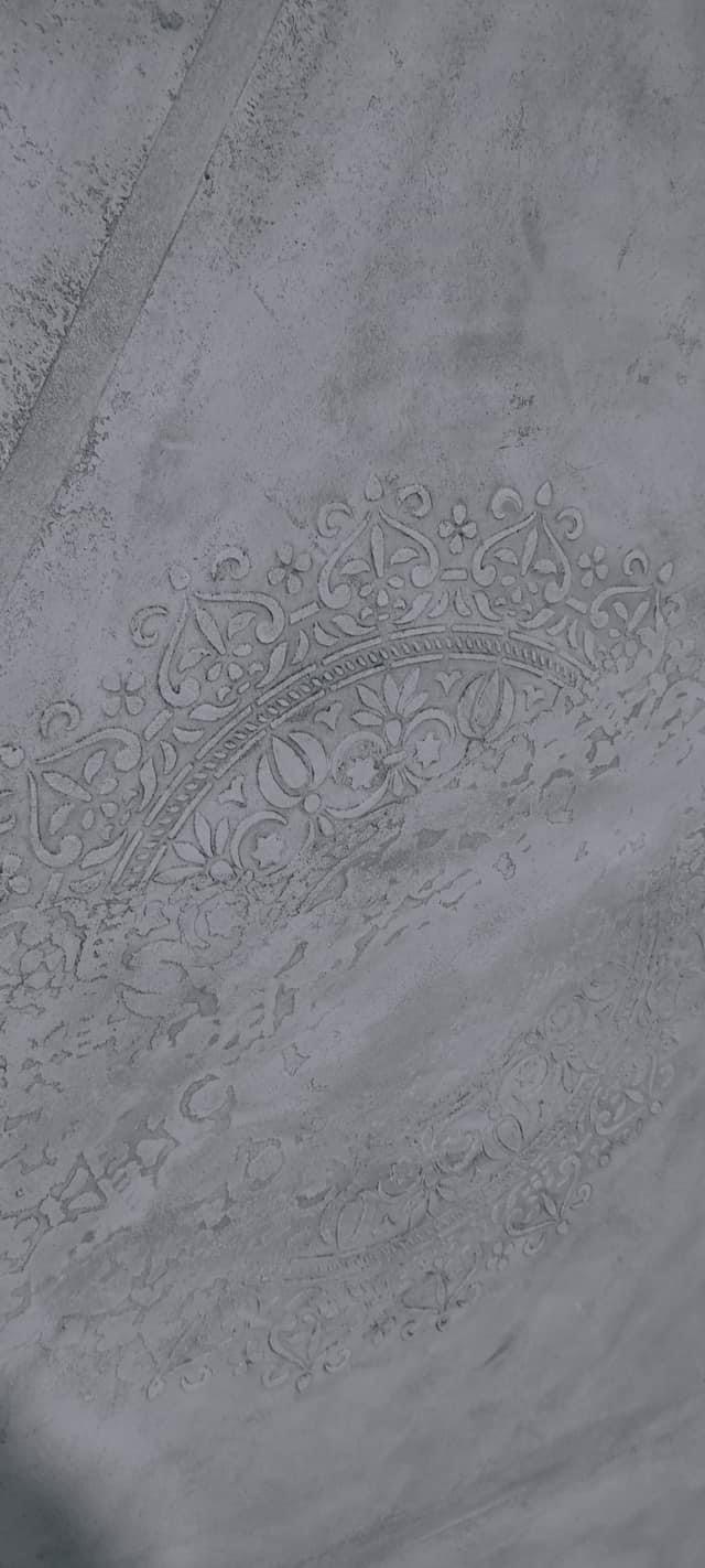 Szara ściana z dekoracyjnym, wypukłym ornamentem w stylu arabskim, wykonana techniką stiuku weneckiego.
