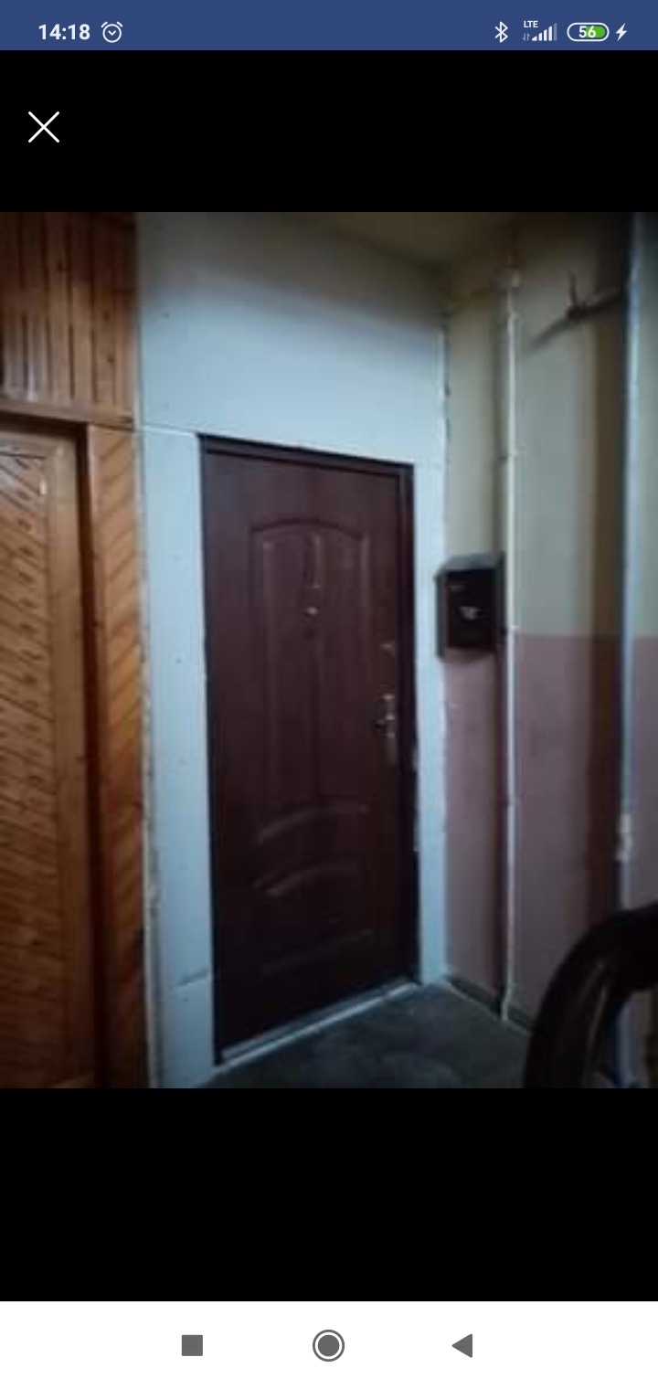 Brązowe drzwi wejściowe, zamontowane wewnątrz klatki schodowej bloku mieszkalnego, widoczna skrzynka na listy.