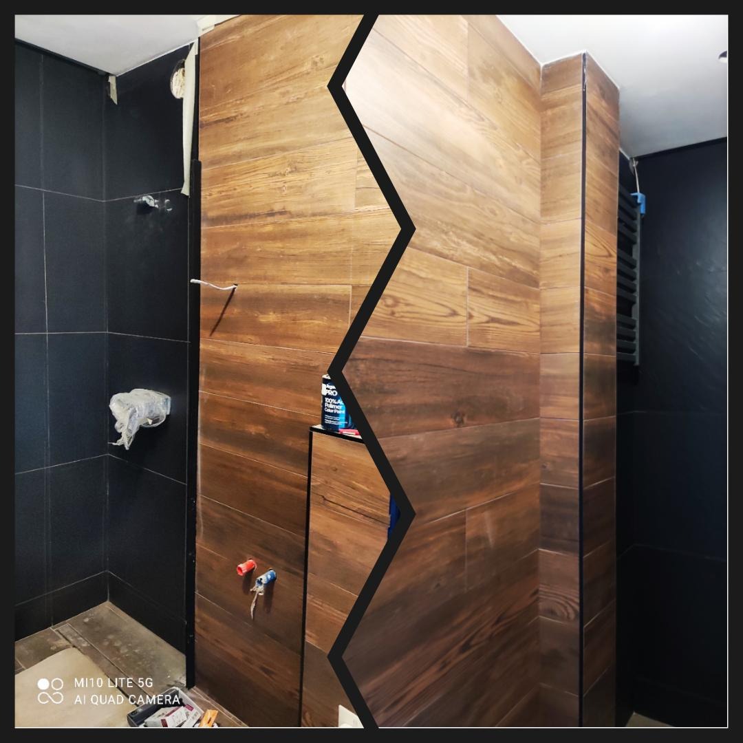 Łazienka w trakcie wykańczania: Połowa ściany wyłożona ciemnymi płytkami, druga połowa panelami imitującymi drewno. Widoczne narzędzia i materiały budowlane.