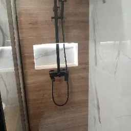 Nowoczesny prysznic z czarną armaturą, drewnopodobnymi płytkami i podświetlaną wnęką na kosmetyki.