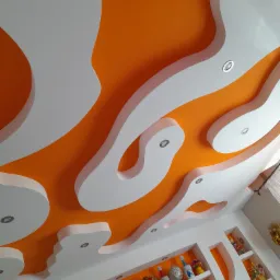 Pomarańczowy sufit z białymi, nieregularnymi elementami dekoracyjnymi i wbudowanymi punktowymi lampami, widok z dołu, oświetlenie dzienne.