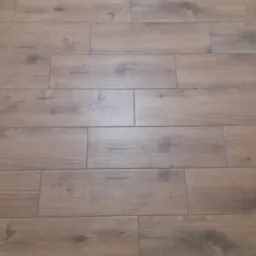 Ułożona podłoga z płytek imitujących drewno, widoczne fugi i struktura drewna.