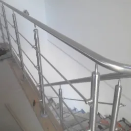 Stalowa balustrada schodowa z poziomymi prętami, zamontowana w jasnym wnętrzu, widoczne elementy montażowe i zabezpieczenia na schodach.