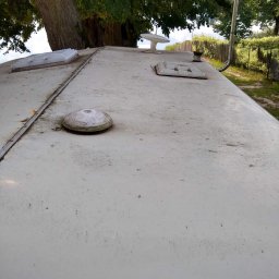 PureSteam - mobilna myjnia parowa - Zabrudzony dach kampera z widocznymi elementami wyposażenia, takim jak okno dachowe, antena i wlot powietrza, na tle drzew i zieleni.