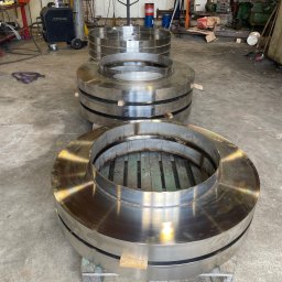 DaMet Damian Napora - Polerowane, spawane pierścienie ze stali na paletach w warsztacie ślusarskim. Widoczne spawy i obróbka metalu. Elementy konstrukcyjne.