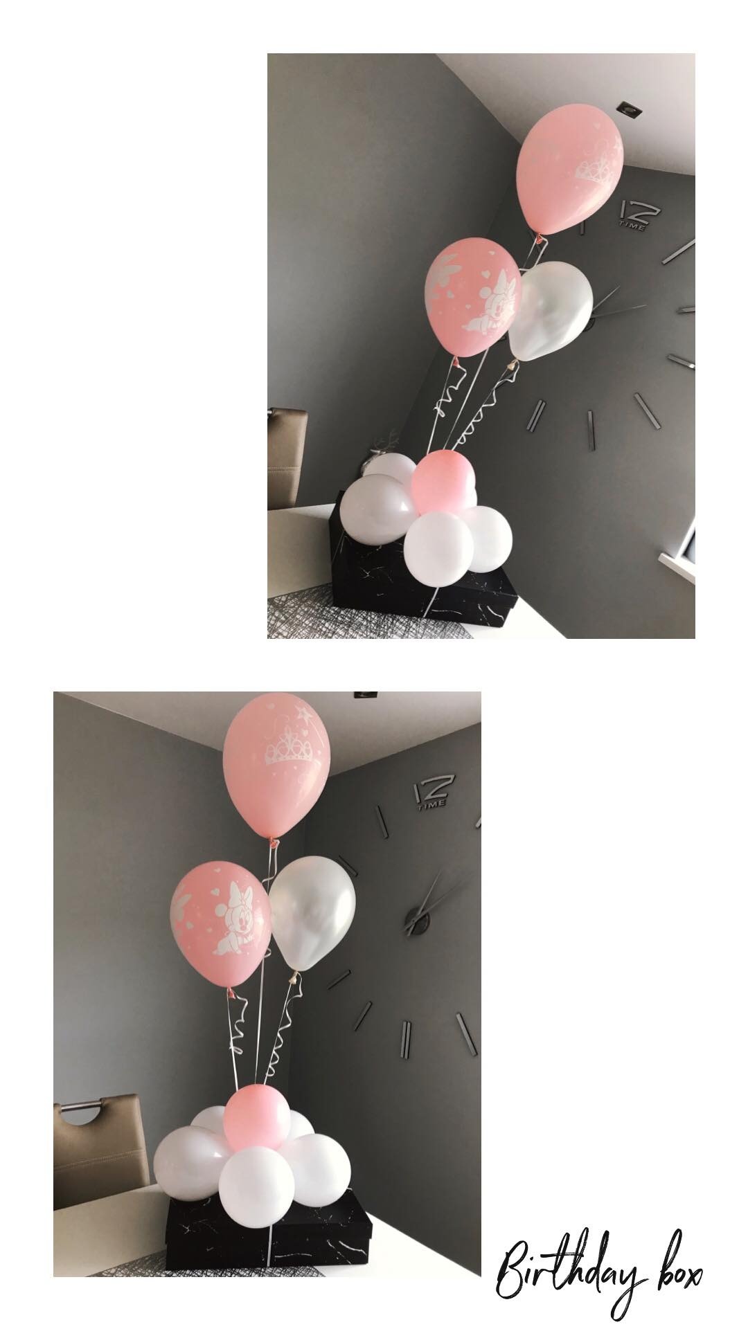 Różowe i białe balony z nadrukami, ułożone na czarno-białym pudełku na tle szarej ściany z zegarem.