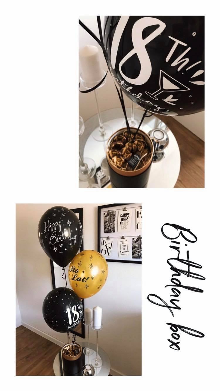 Dekoracje urodzinowe: balony z napisami 'Happy Birthday', 'Sto Lat!', '18th', pudełko z prezentami, świece na szklanych świecznikach, plakaty na ścianie, kompozycja na małym stoliku.