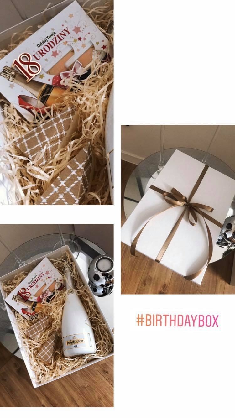 Zestaw prezentowy na 18 urodziny: białe pudełko wypełnione siankiem, butelka białego wina musującego Monte Santi Ice, kartka urodzinowa z liczbą 18, małe prezenty w brązowym papierze, obok...