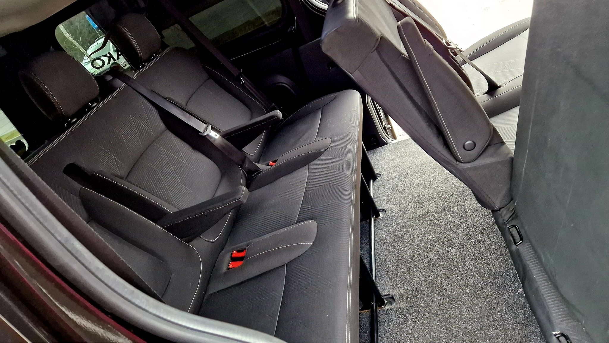 Wnętrze busa z rozłożonymi, czarnymi fotelami z zagłówkami i pasami bezpieczeństwa, widok z boku