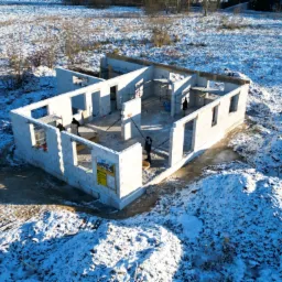 Stan surowy otwarty domu jednorodzinnego w Słupsku, budowanego zimą, widok z góry na ośnieżony teren budowy i częściowo postawione ściany z bloczków.