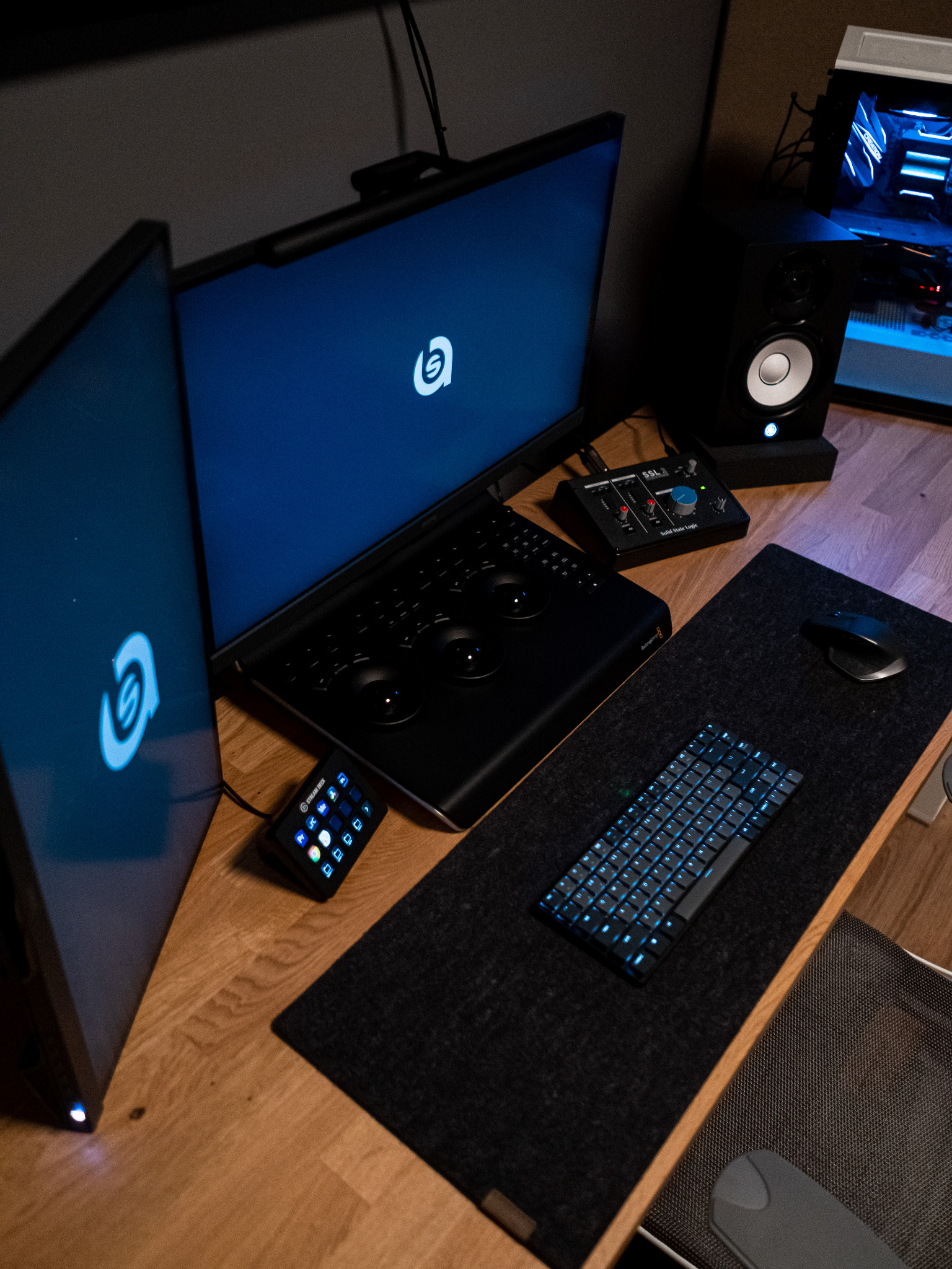 Stanowisko do montażu wideo z dwoma monitorami wyświetlającymi logo, klawiaturą z podświetleniem, panelem sterowania kolorem, mikserem audio SSL i głośnikiem studyjnym Yamaha.