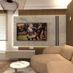 MODERN DESIGN Monika Nowak - Nowoczesny salon z beżową sofą, marmurową ścianą TV i drewnianymi akcentami. Okno z żaluzjami, designerskie lampy wiszące i okrągły stolik kawowy.