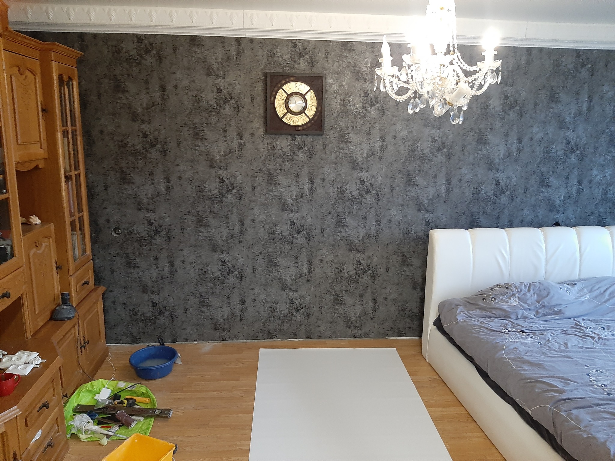 Pokój po zmianie koloru ścian na szaro-czarny, widoczny fragment łóżka, narzędzia malarskie i zabezpieczona podłoga.