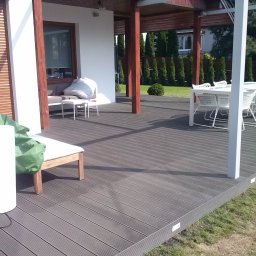 RedWood - Nowoczesny taras z kompozytowych desek w kolorze szarości, wyposażony w białe meble ogrodowe i oświetlenie LED wbudowane w obrzeża.