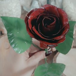 NITREX Rafał Nita - Czerwona metalowa róża z zielonymi liśćmi, trzymana w dłoni, z widocznymi danymi kontaktowymi firmy w tle.