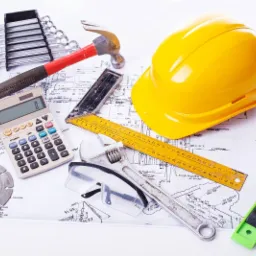 Plan techniczny z narzędziami: kask, poziomica, klucze, młotek, kalkulator, okulary ochronne, miarka i klucz nastawny.