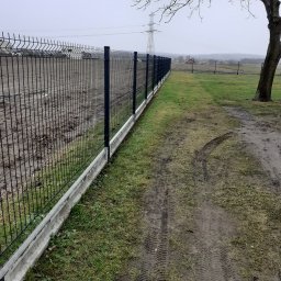 Ogrody z duszą Nie przesadzaj S.C - Nowoczesne ogrodzenie panelowe z podmurówką betonową, widoczne ślady opon na trawie i drzewo bez liści w tle.