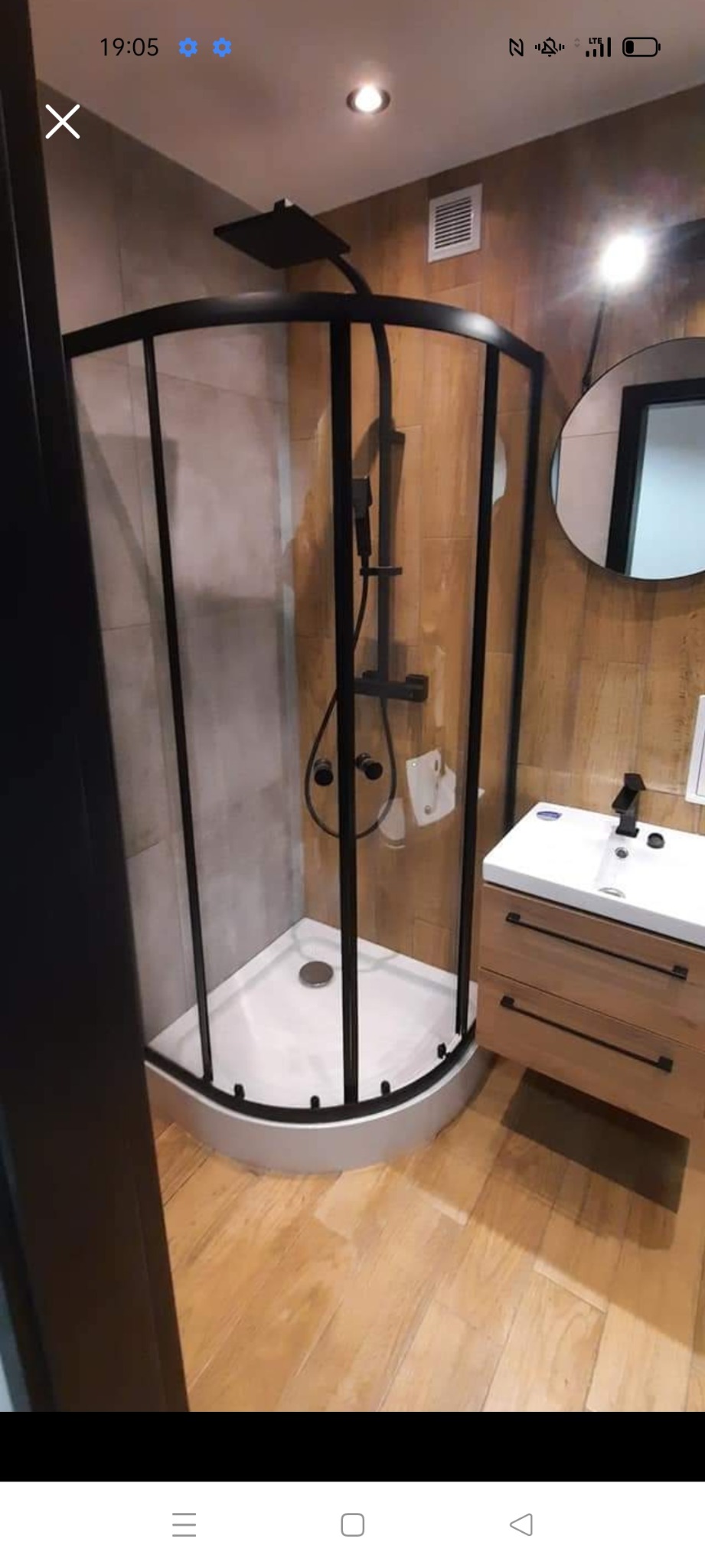 Nowoczesna łazienka z narożną kabiną prysznicową z czarnymi ramami, drewnianą podłogą i szafką pod umywalką z drewnianymi frontami.