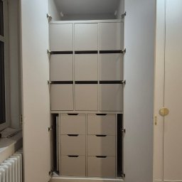 Manity Design Mateusz Łagiewa - Wnętrze szafy na wymiar z szufladami i półkami, widoczne otwarte drzwi i zabezpieczenia podłogi kartonem.