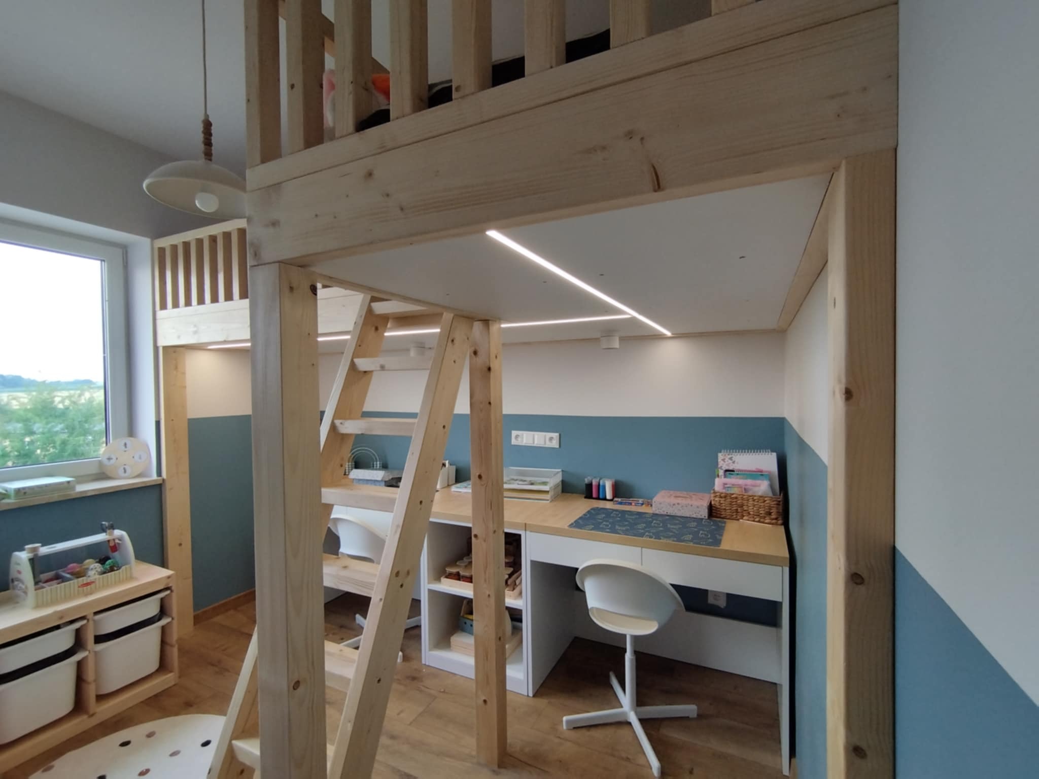 Pokój dziecięcy z antresolą i biurkiem, drewniane elementy, białe ściany z błękitnym akcentem. Dostęp po drabince, oświetlenie LED, zabawki i akcesoria.