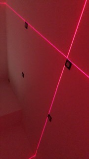 Wyznaczanie punktów instalacji elektrycznej za pomocą lasera krzyżowego na ścianie w trakcie remontu. Widoczne puszki instalacyjne.