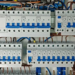 Rozdzielnica elektryczna z zainstalowanymi bezpiecznikami automatycznymi Schrack i okablowaniem, widok z bliska na elementy zabezpieczające instalację.