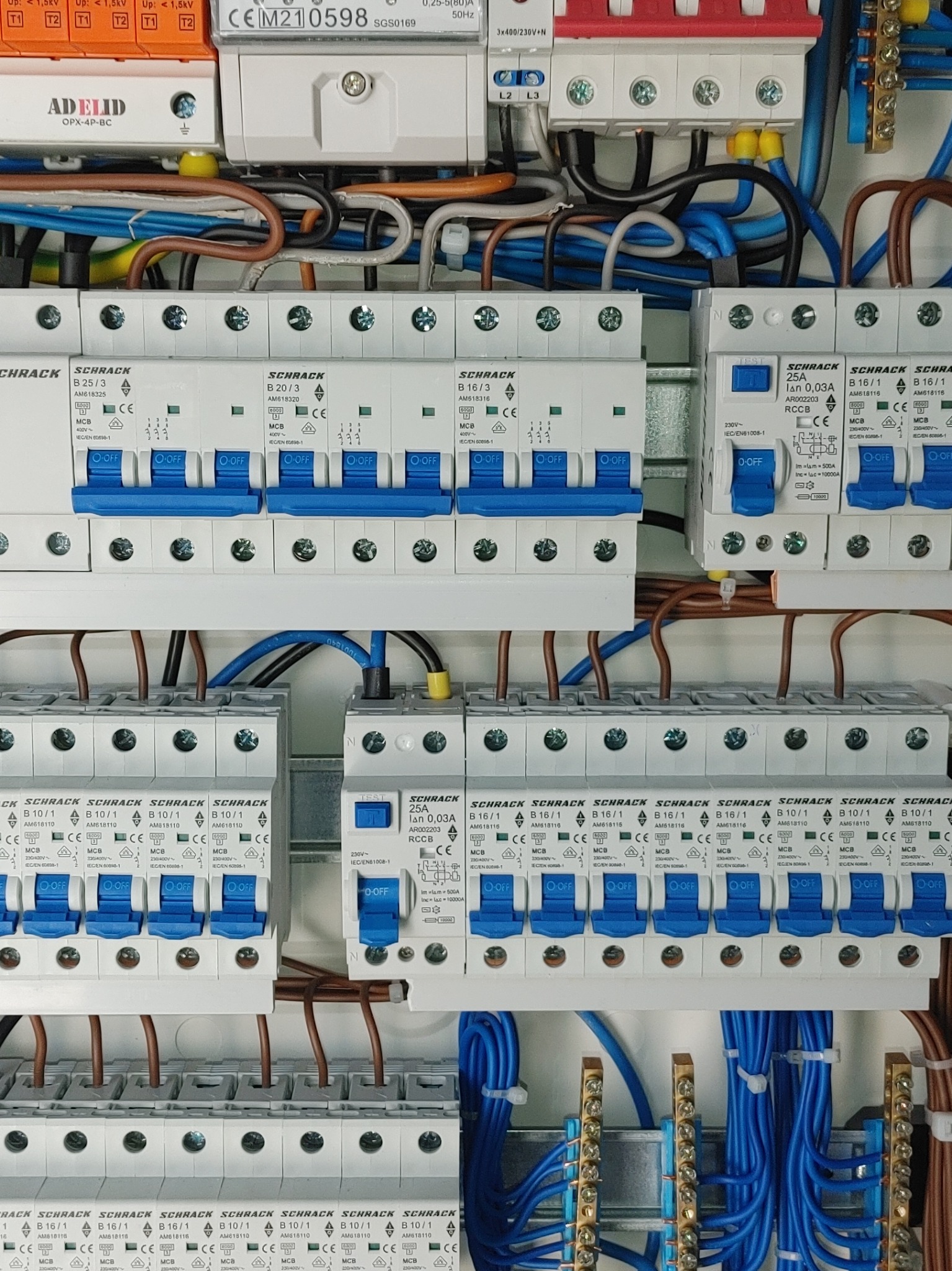 Rozdzielnica elektryczna z zainstalowanymi bezpiecznikami automatycznymi Schrack i okablowaniem, widok z bliska na elementy zabezpieczające instalację.