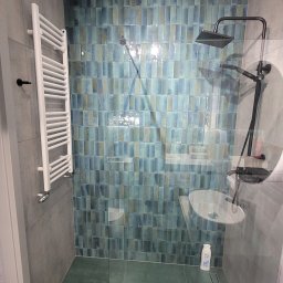 MKDom - Nowoczesna łazienka z kabiną prysznicową typu walk-in, wykończona turkusową mozaiką na ścianie, szarymi płytkami na pozostałych ścianach i podłodze, z białym grzejnikiem drabinkowym i czarną...