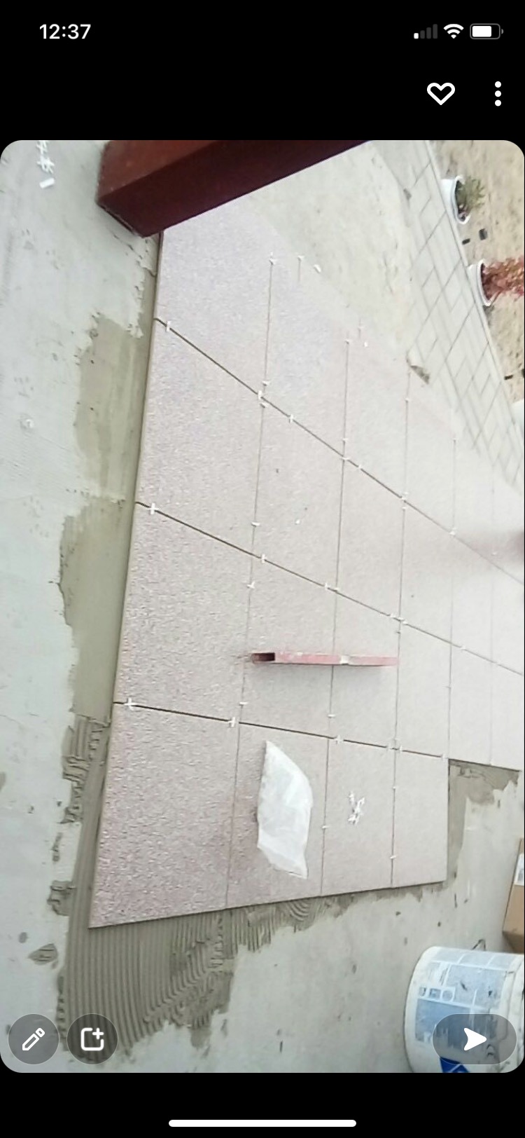 Układanie płytek elewacyjnych z użyciem krzyżyków dystansowych, widoczny fragment ściany z nałożonym klejem i poziomica.