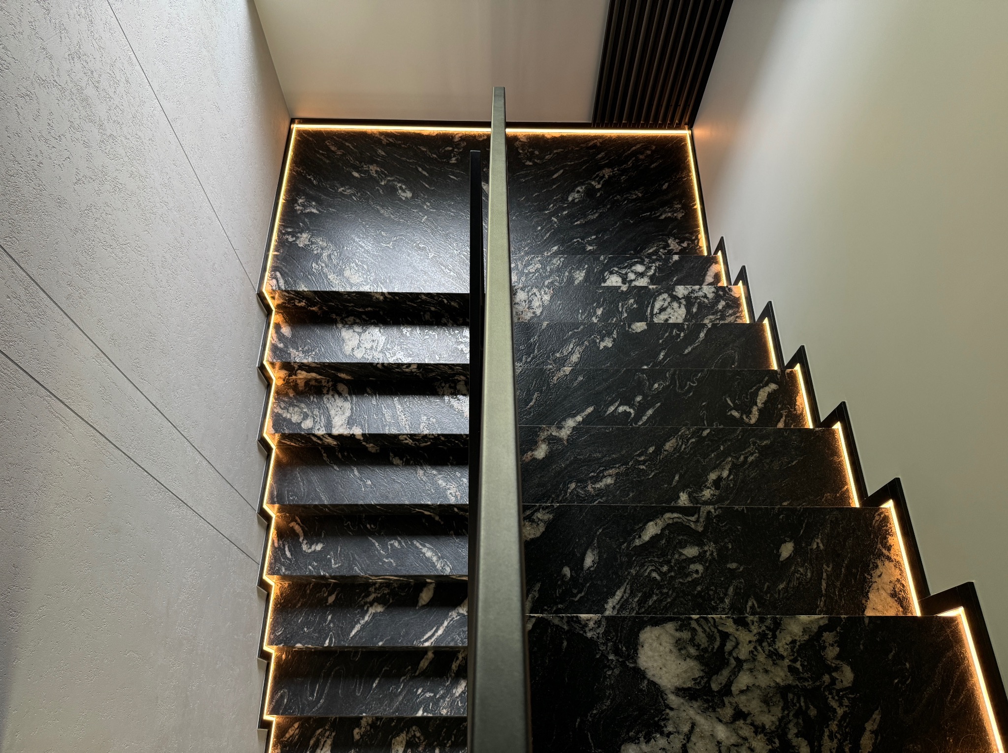 Nowoczesne schody z czarnego kamienia z podświetleniem LED, widok z góry. Minimalistyczna balustrada, eleganckie wykończenie.