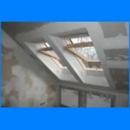 Montaż płyt G-K na poddaszu, widoczne stelaże okien dachowych i fragmenty ścian działowych przed szpachlowaniem.