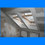 Montaż płyt G-K na poddaszu, widoczne stelaże okien dachowych i fragmenty ścian działowych przed szpachlowaniem.