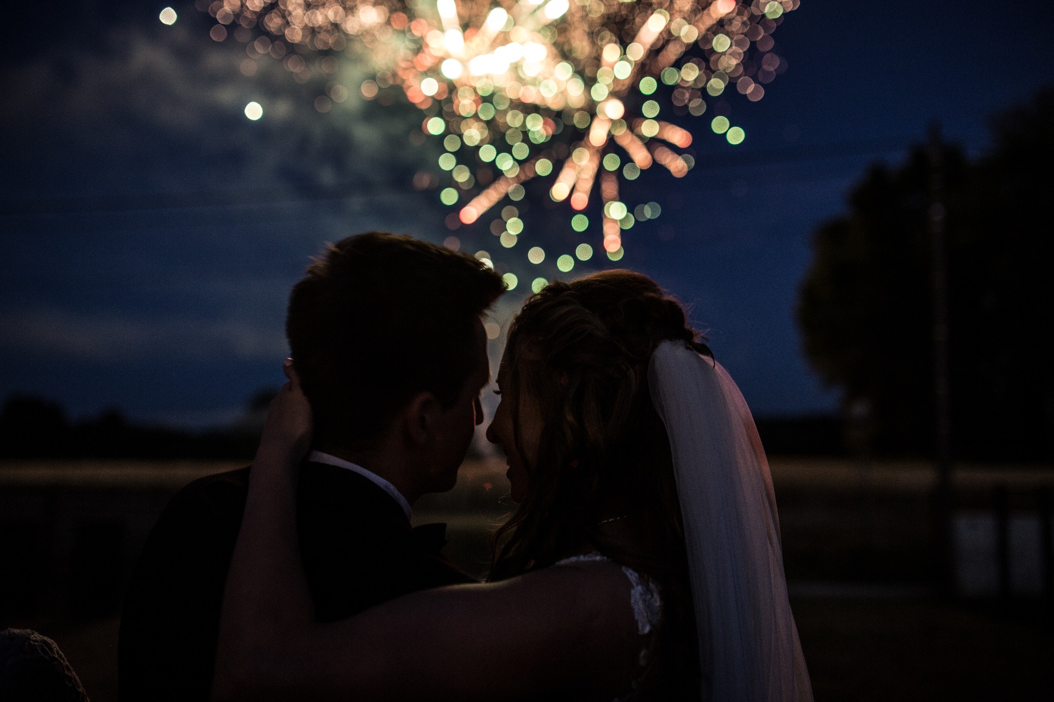 Para młoda w Bielsku-Białej obejmuje się na tle nocnego nieba rozświetlonego fajerwerkami, tworząc romantyczną i uroczystą atmosferę.