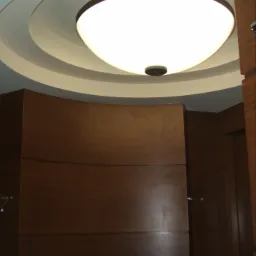 Nowoczesne oświetlenie sufitowe w łazience z drewnianymi panelami ściennymi i zaokrąglonym sufitem.