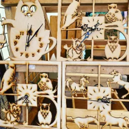 Ręcznie robione, drewniane zegary z motywami zwierzęcymi: kot w filiżance, sowy i konie, każdy umieszczony w kwadratowej ramce.