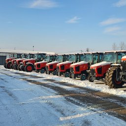 Sosaan - Rząd nowych, czerwonych traktorów Kubota M7152 na śniegu przed magazynem, w zimowym słońcu.