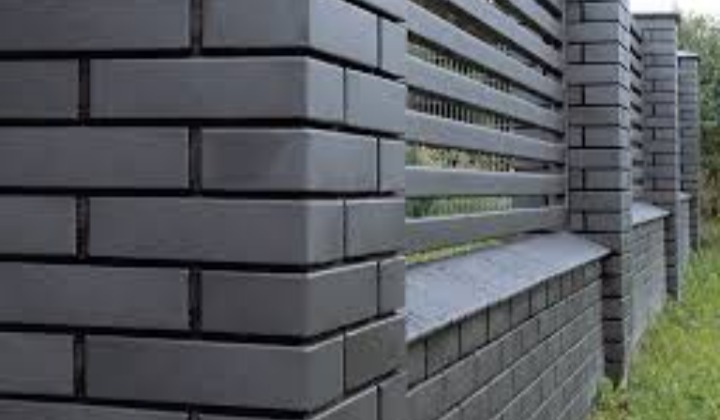 Nowoczesne ogrodzenie z szarej cegły klinkierowej z poziomymi przęsłami w Białej Podlaskiej, widok z bliska na filar i fragment muru.