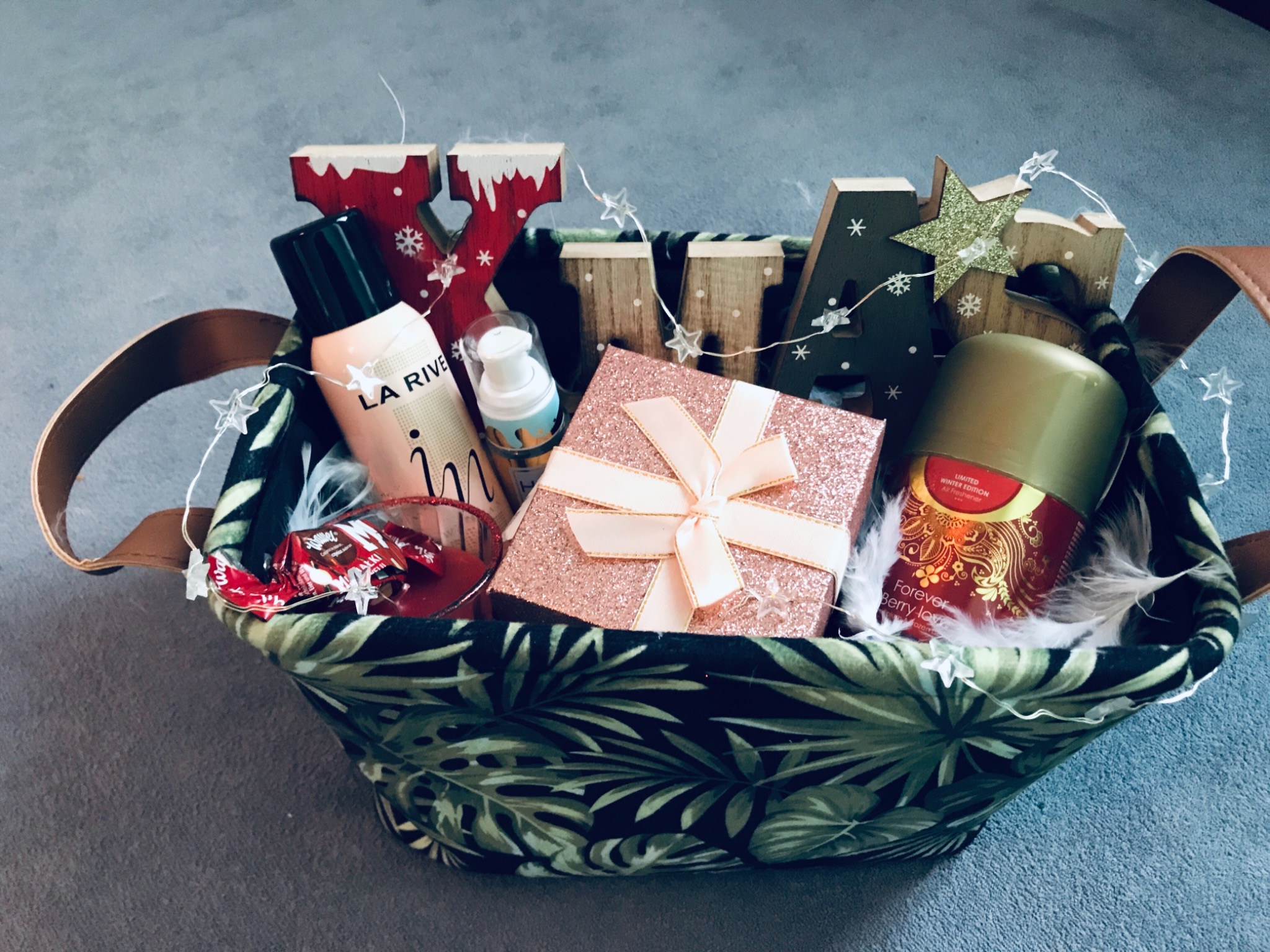 Kosz prezentowy z kosmetykami La Rive, odświeżaczem powietrza Forever Berry Love, ozdobnym pudełkiem z kokardą, słodyczami i dekoracjami świątecznymi z drewnianymi literami i lampkami w kształcie...