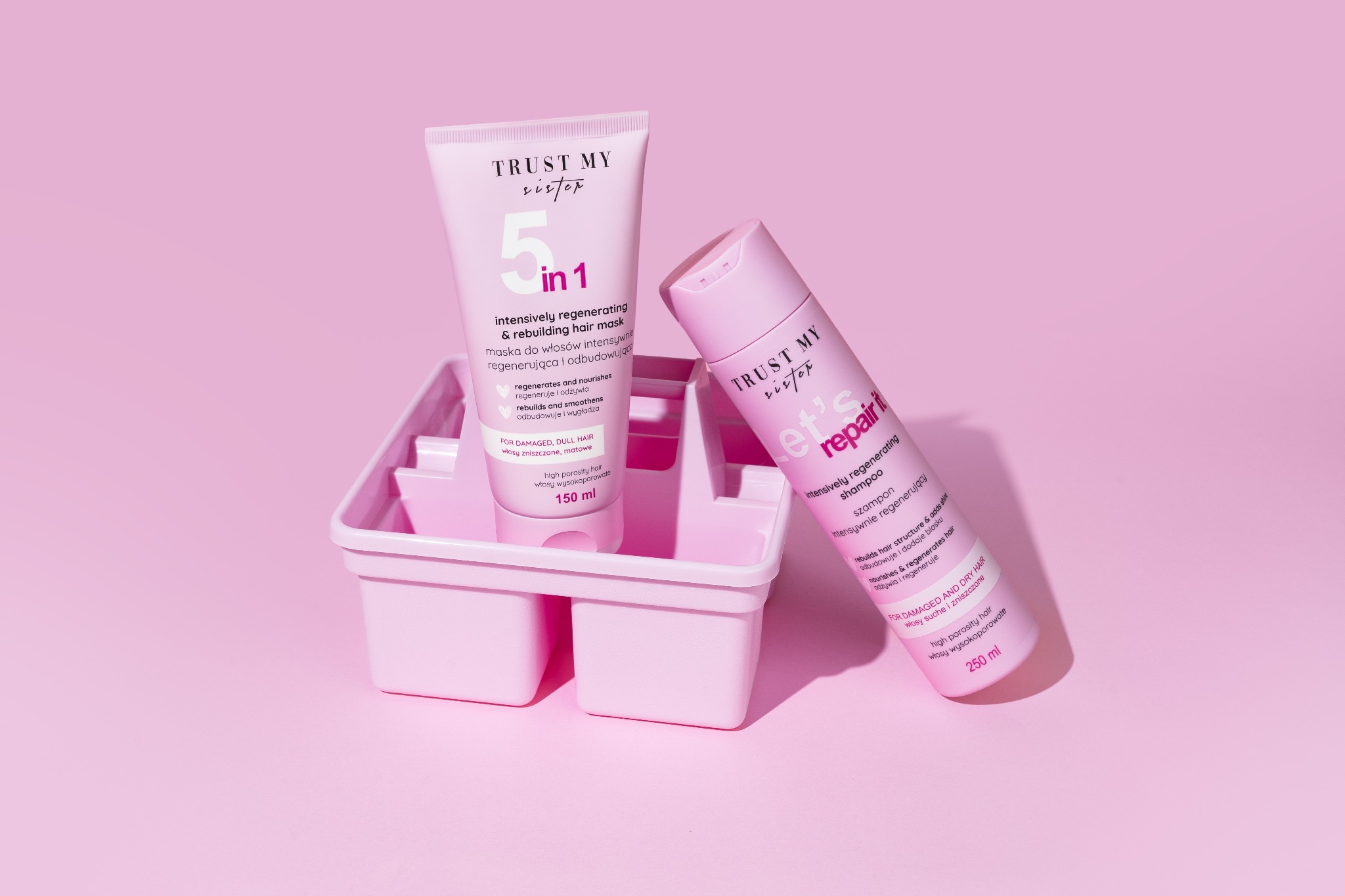 Różowa maska do włosów w tubce i szampon w butelce, umieszczone w różowym pojemniku na tle w odcieniu pudrowego różu.