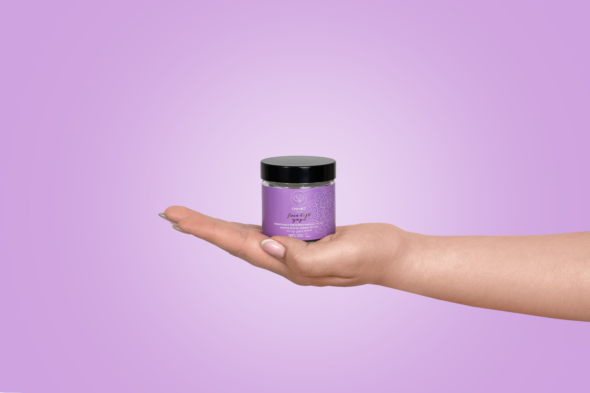 Dłoń prezentuje fioletowy słoiczek kremu do twarzy 'Face Lift Yoga' na tle liliowego gradientu.