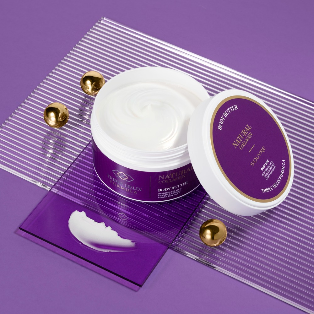 Otwarty słoik z białym kremem, obok próbka na fioletowej płytce i złote kulki. Całość na fioletowym tle z prążkami. Krem Natural Collagen Body Butter.