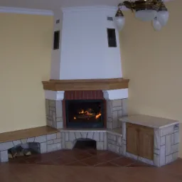 Kątowy wkład z paleniskiem obudowany kamieniem i drewnem, z drewnianą półką na drewno i szafką boczną, płomienie widoczne przez szybę.