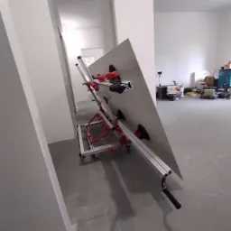 Płyta gipsowo-kartonowa zamocowana na specjalistycznym stojaku z przyssawkami w surowym wnętrzu podczas prac wykończeniowych.